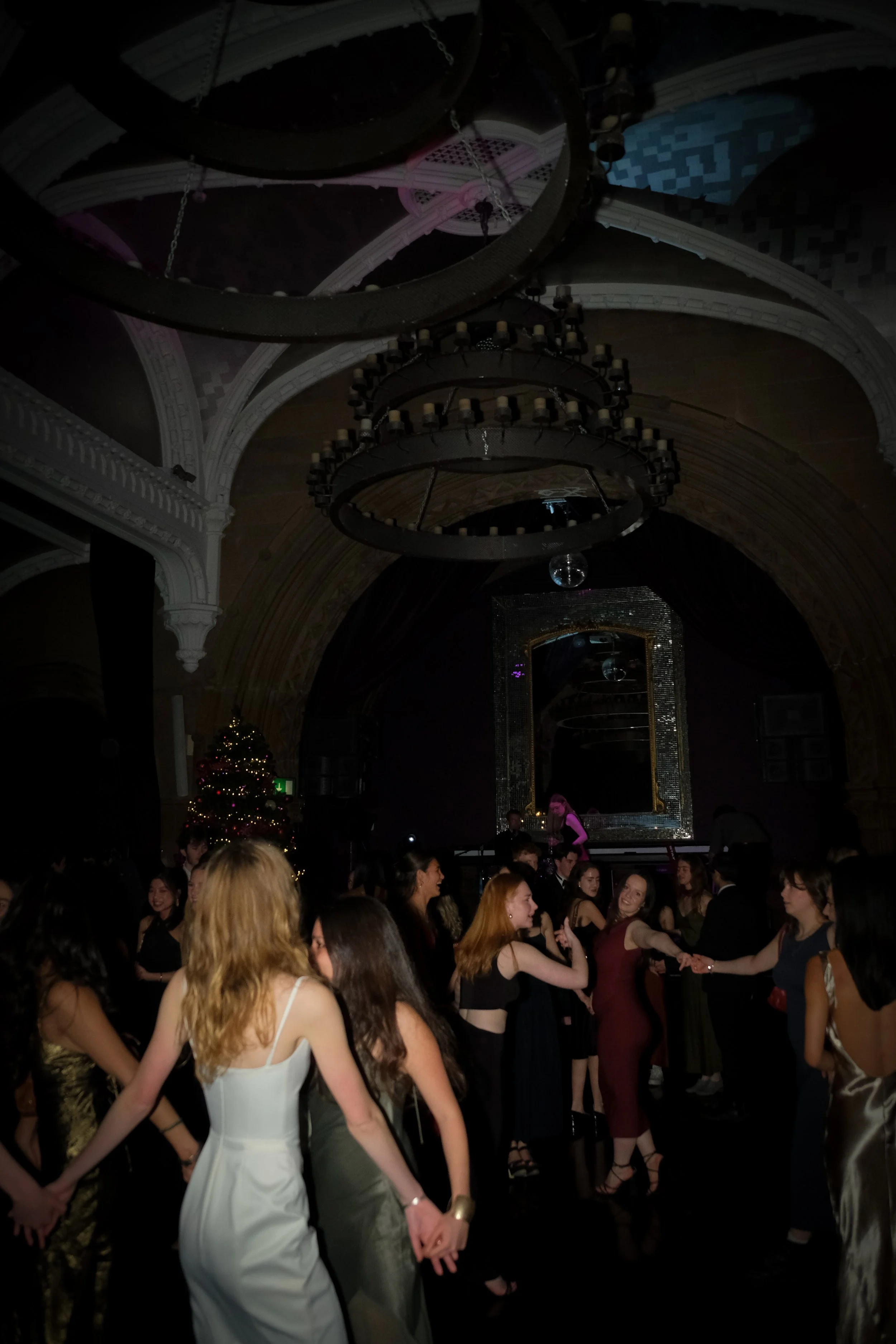 Group of women dancing and having fun at a party with a Christmas tree in the background.