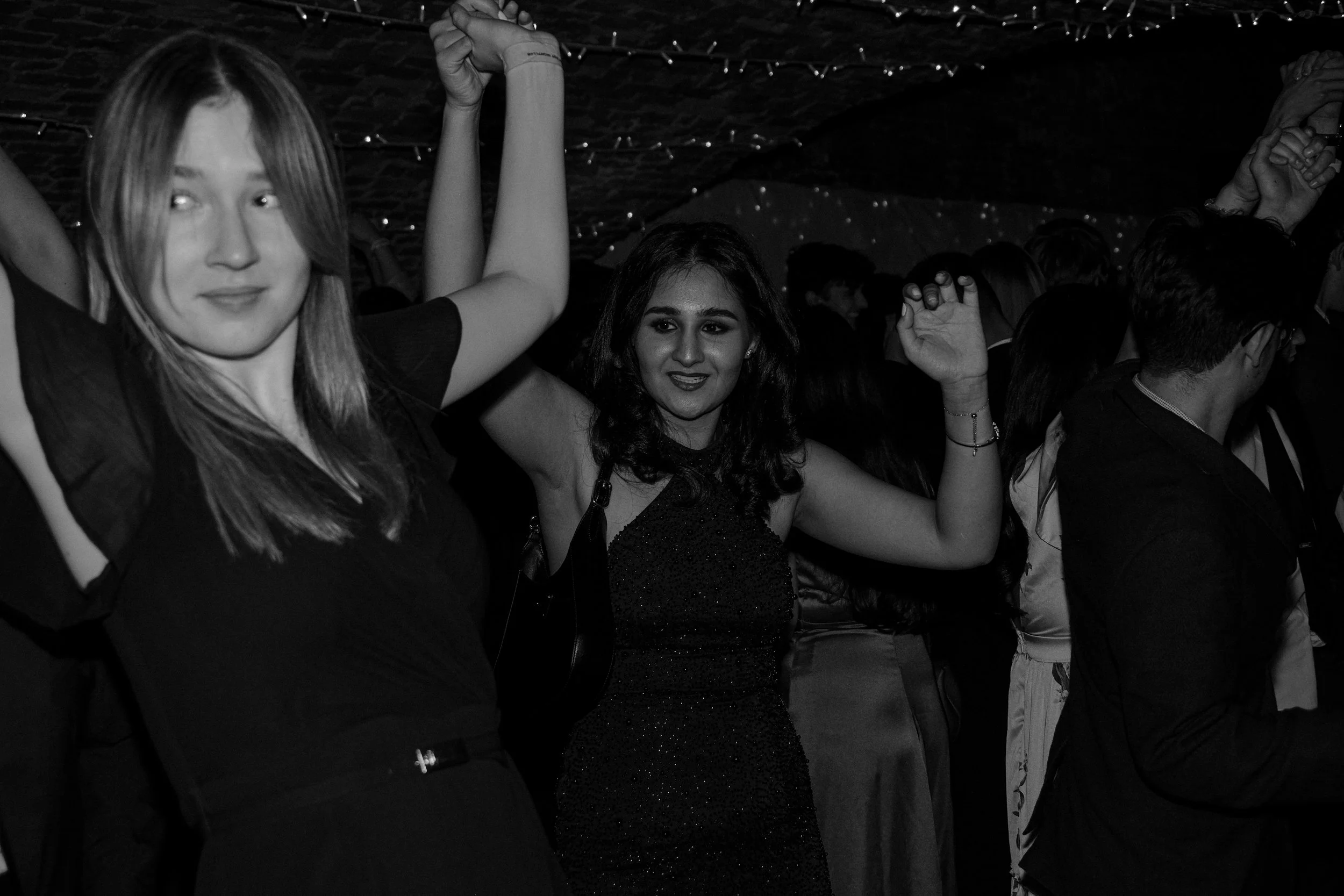 Women dancing at a crowded party or celebration in a dimly lit venue.