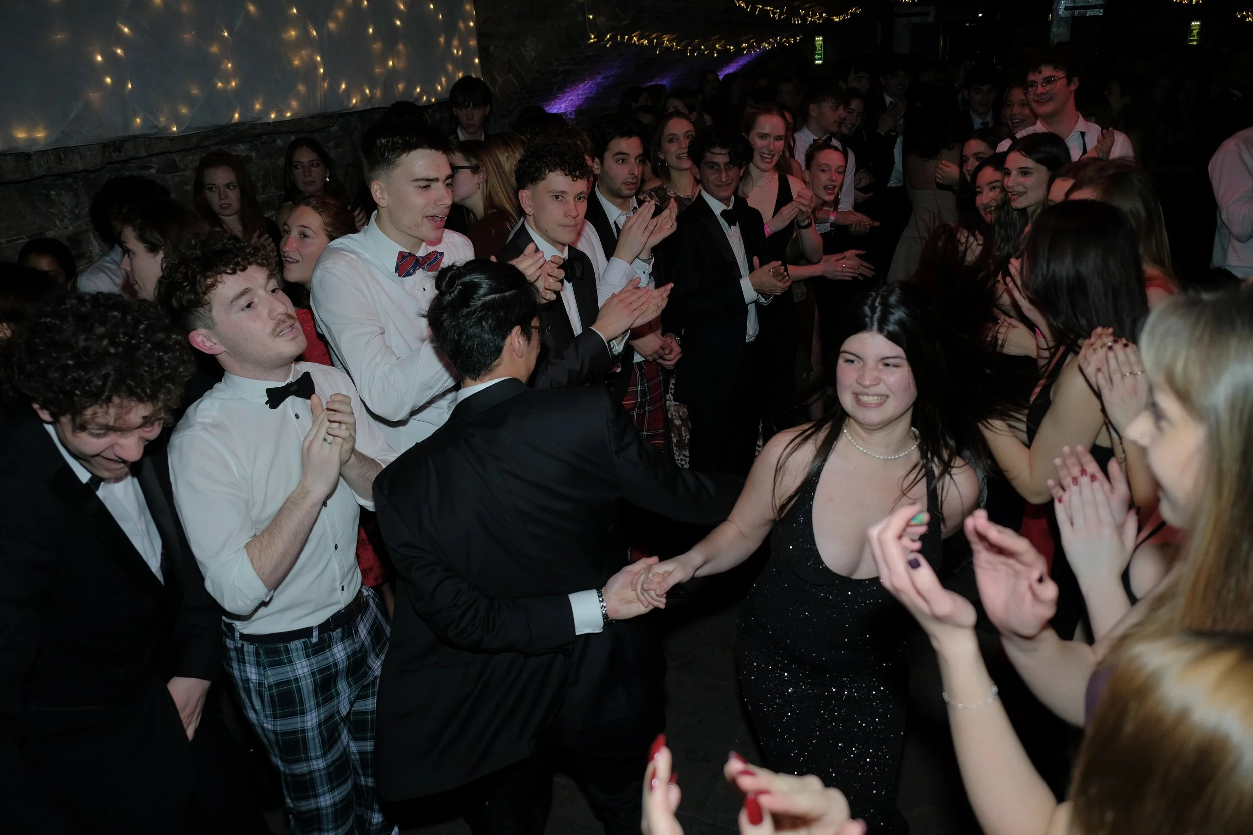 People dancing and smiling at a lively event or party, with a decorated and illuminated background.