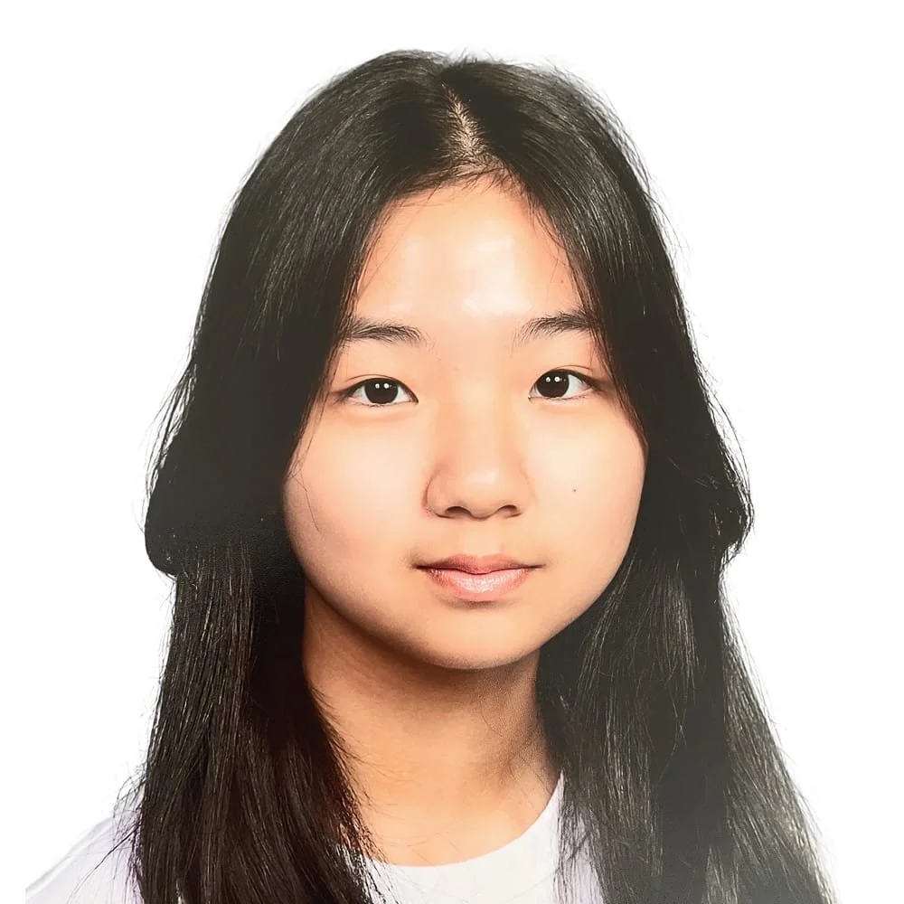 A portrait of a young Asian girl with long black hair and a slight smile, against a white background.