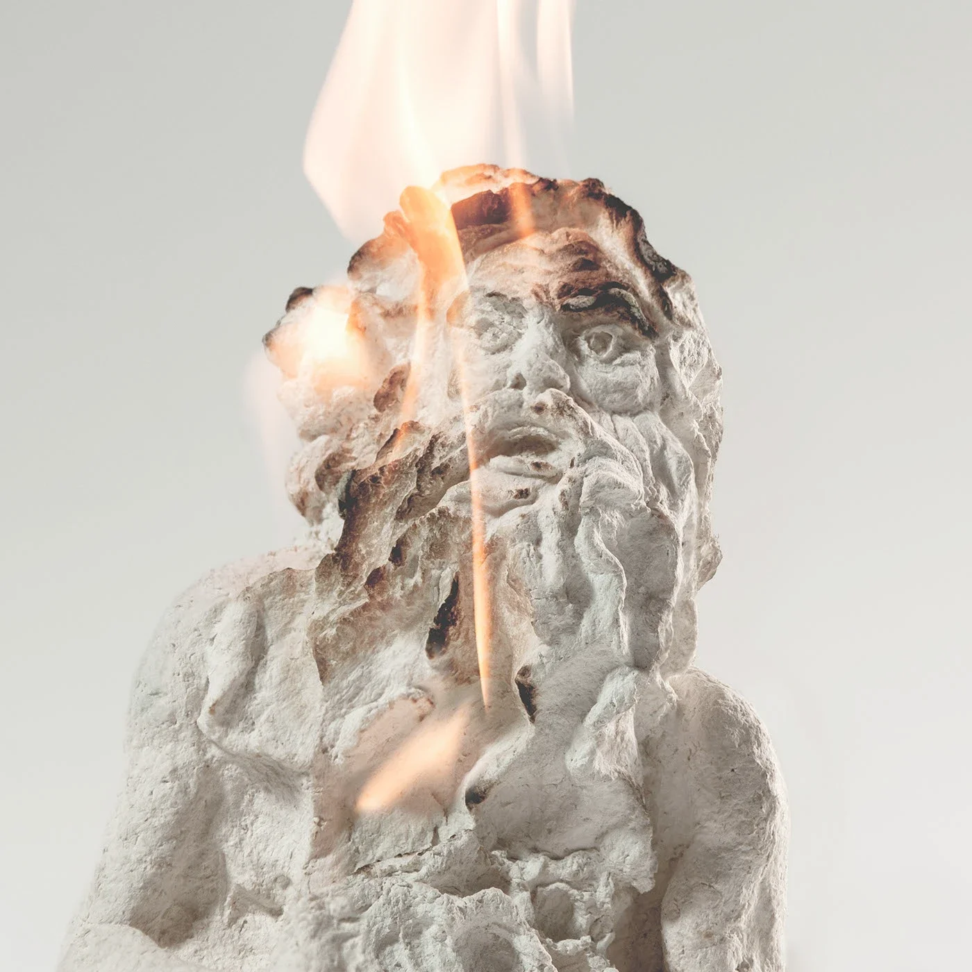 Estátua de um homem com barba olda, sendo que uma das partes de seu rosto está em chamas.