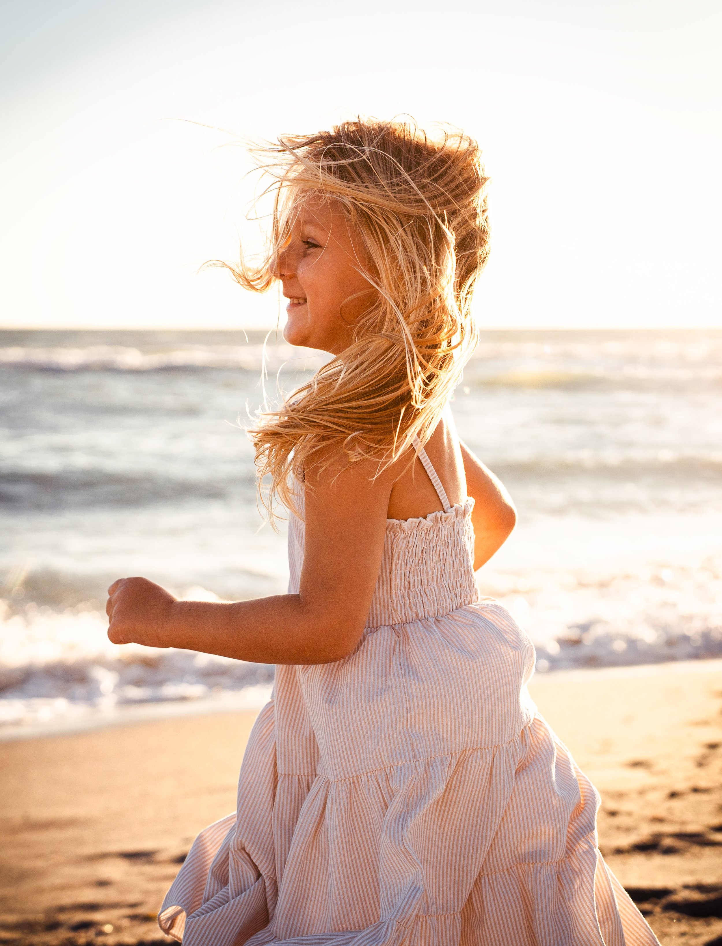 Family Photos featuring a child running on the beach.