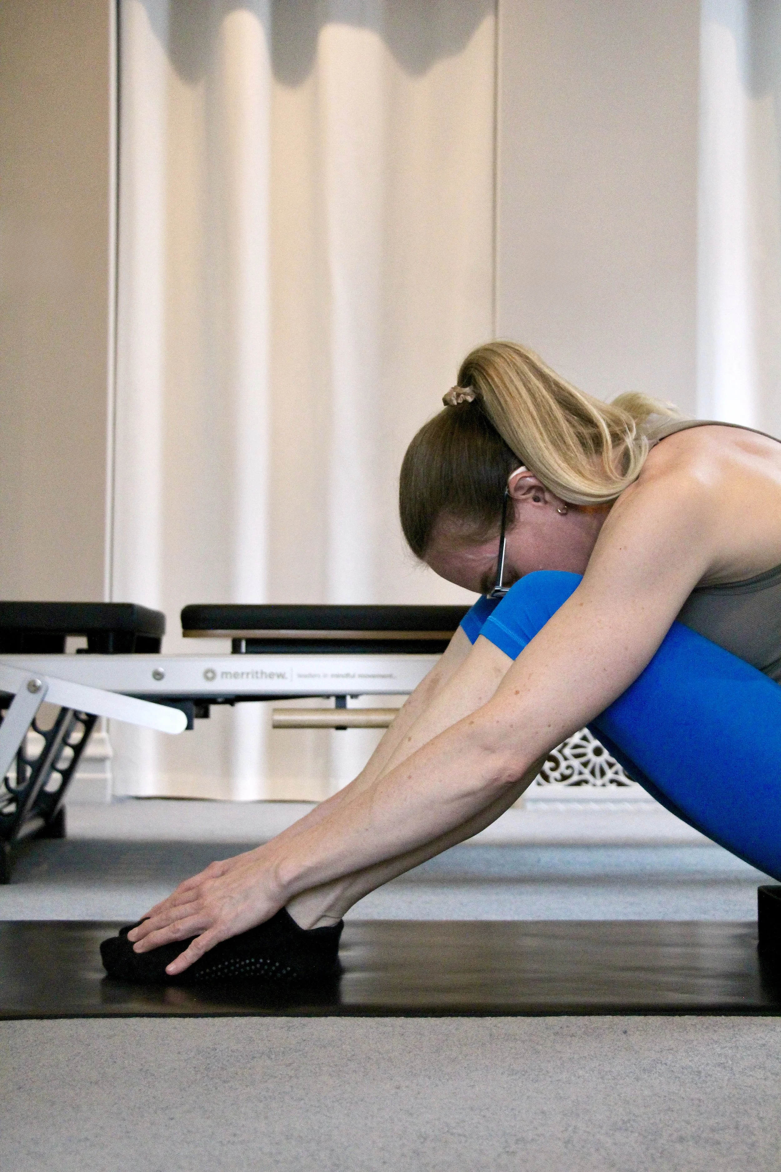woman performing breathing flexed forward on pilates mat
