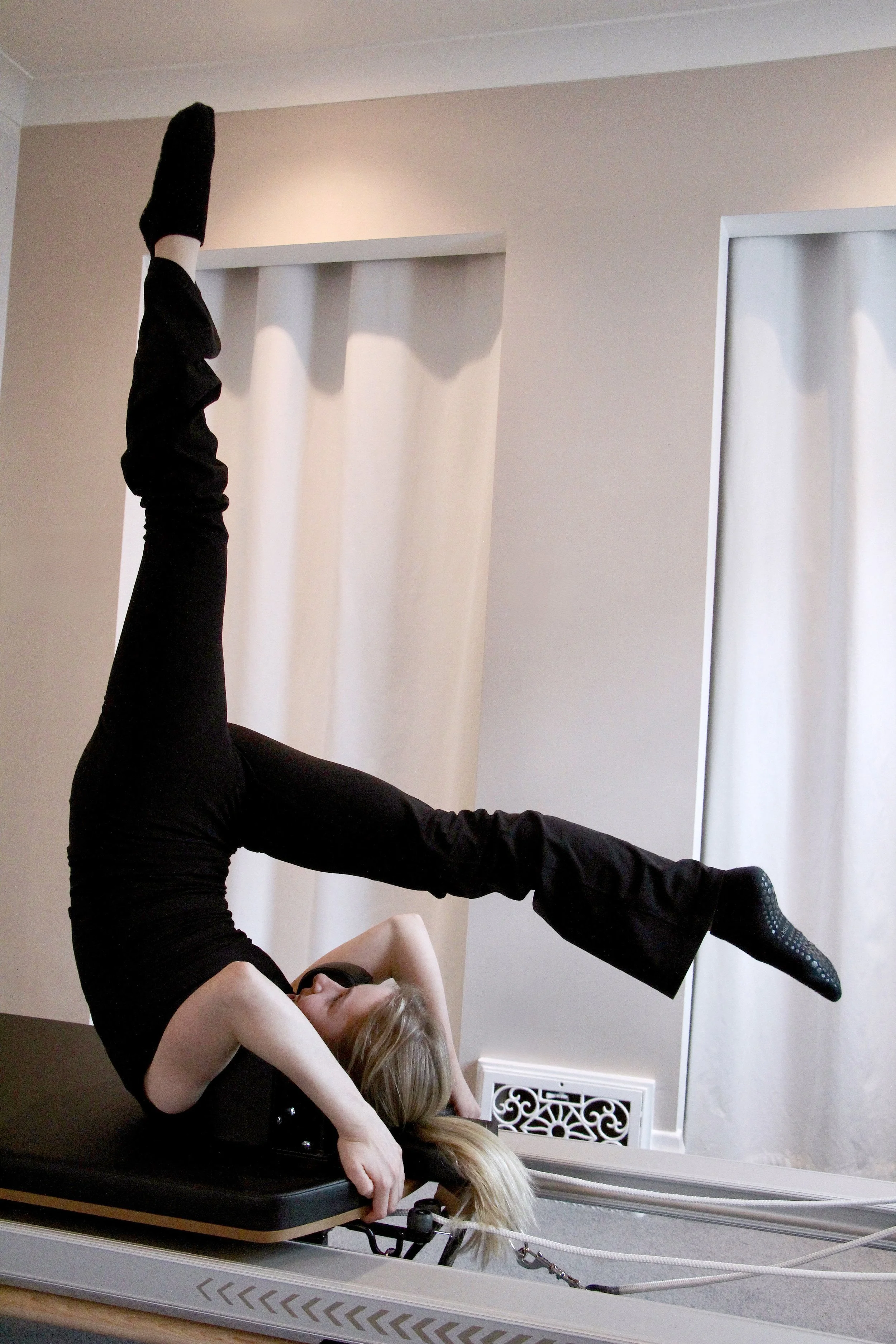 strong pilates client performing advanced movement on reformer