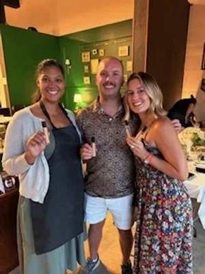 Three professionals in business attire conducting a perfume or essential oil product demonstration at a corporate event or conference.