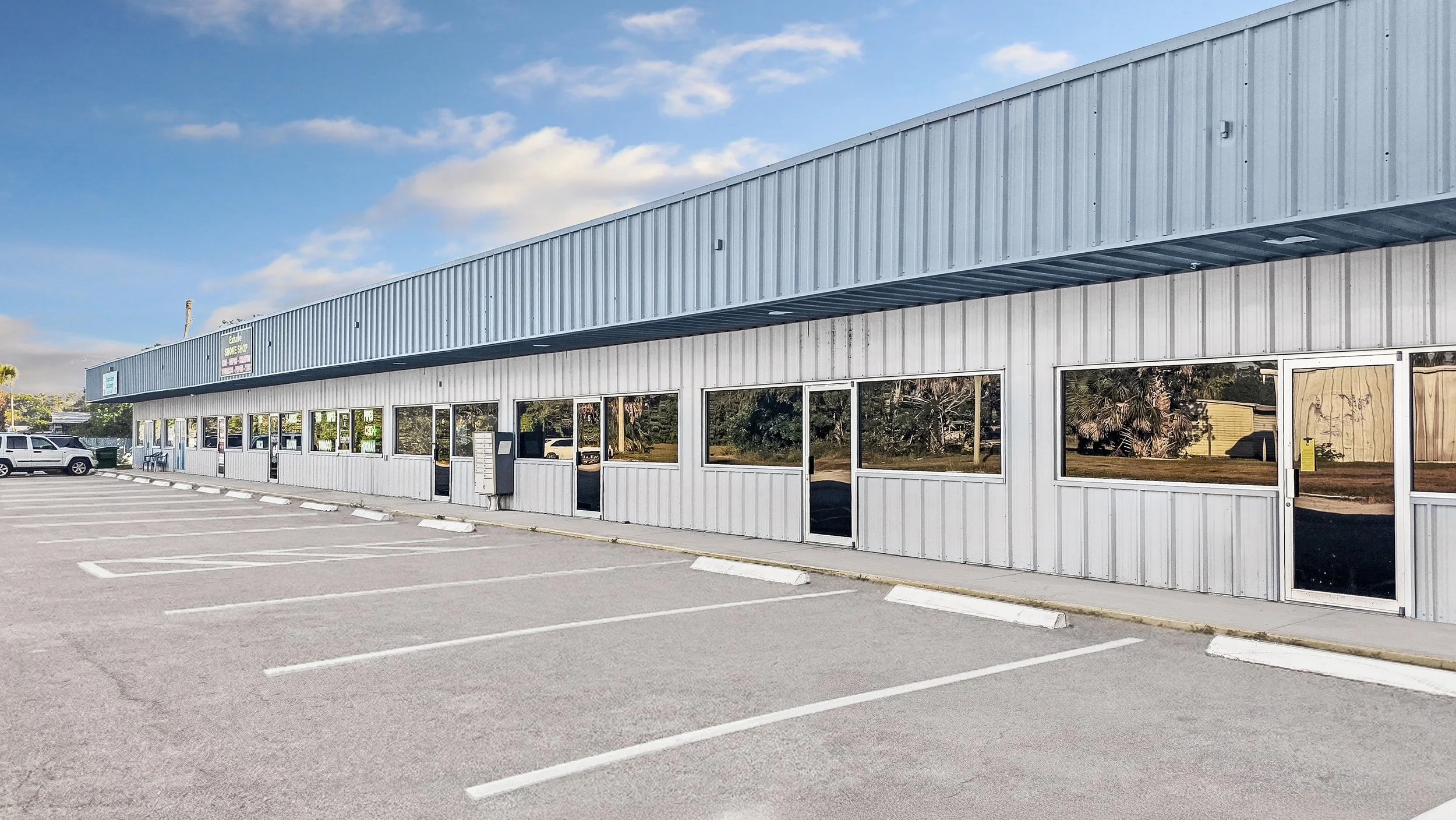 A large retail building with a sign that reads 'Beverly's Delights,' and a parking lot with a few parked cars and shopping carts.
