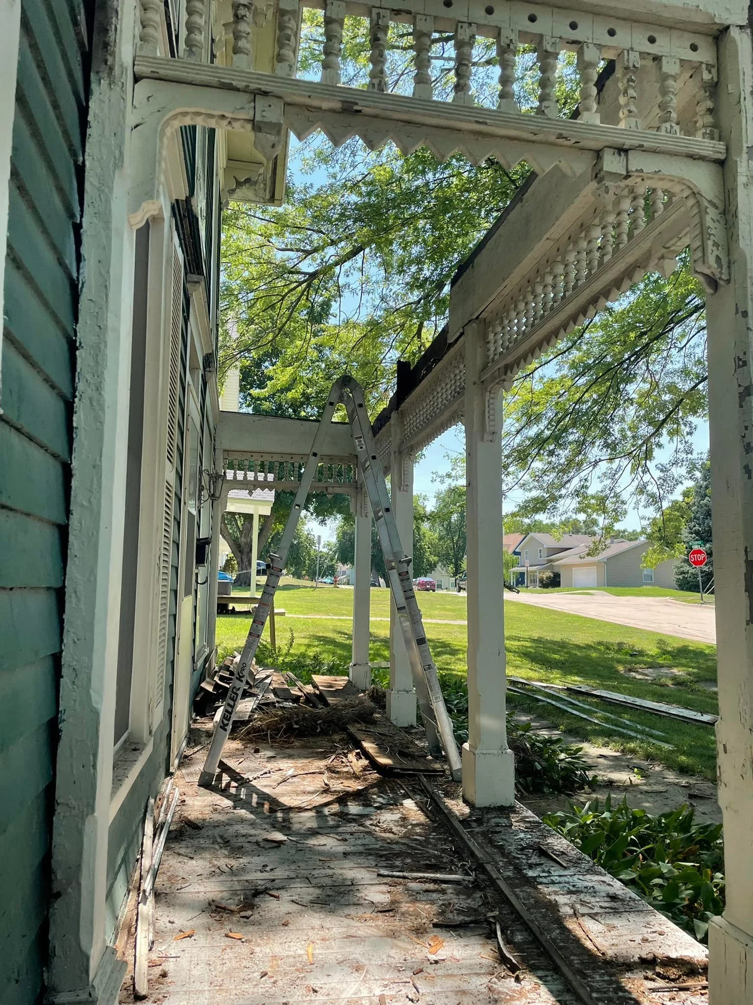Damaged porch under restoration with original trim and railing details carefully preserved. Rural Renovation restoring the structure of a historic home in Nodaway County, Missouri.