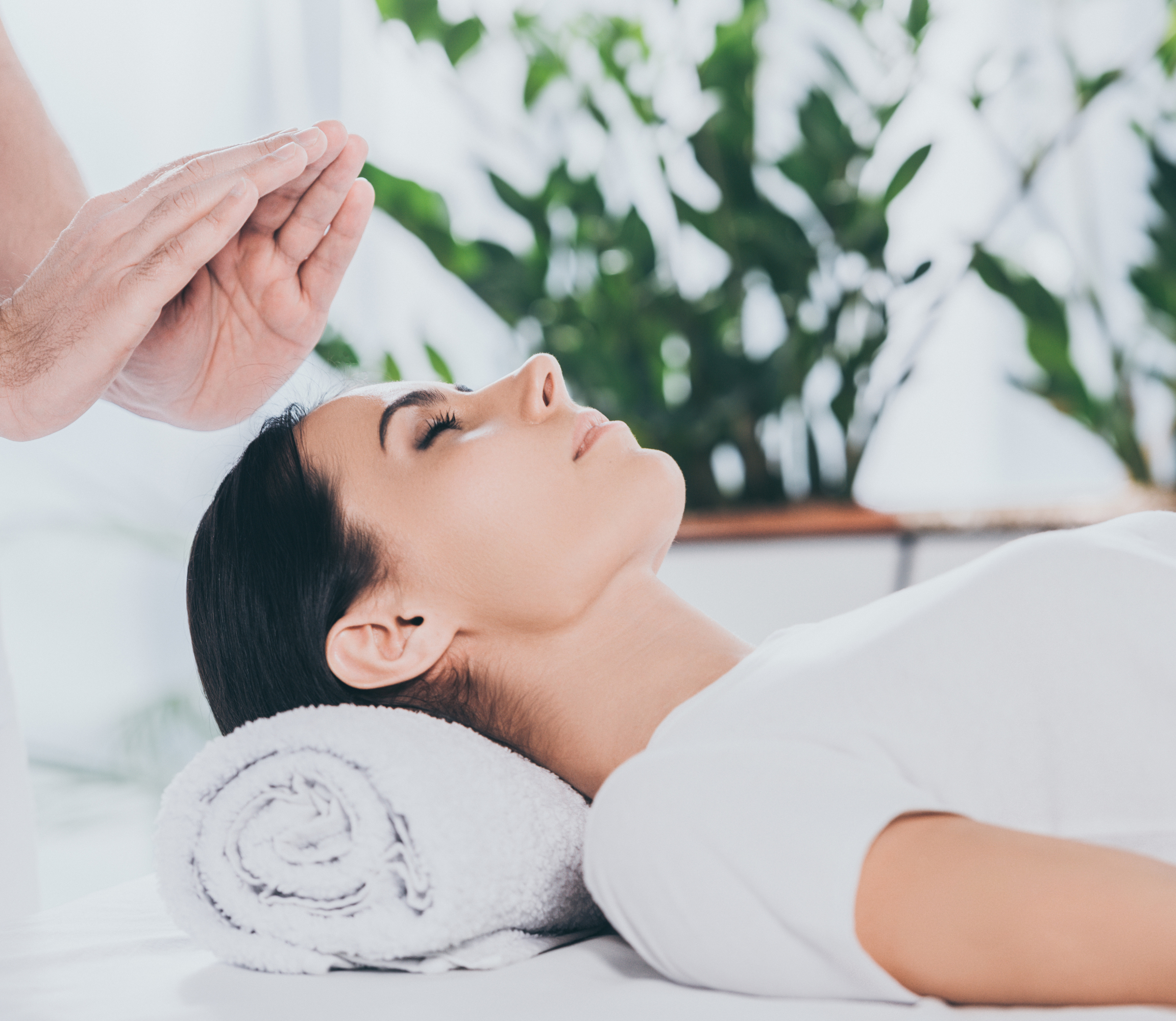 Healing hands hovering over woman's crown chakra.