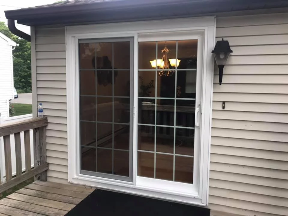 A sliding glass door leading to a deck outside a house, with a water bottle on the wooden railing.