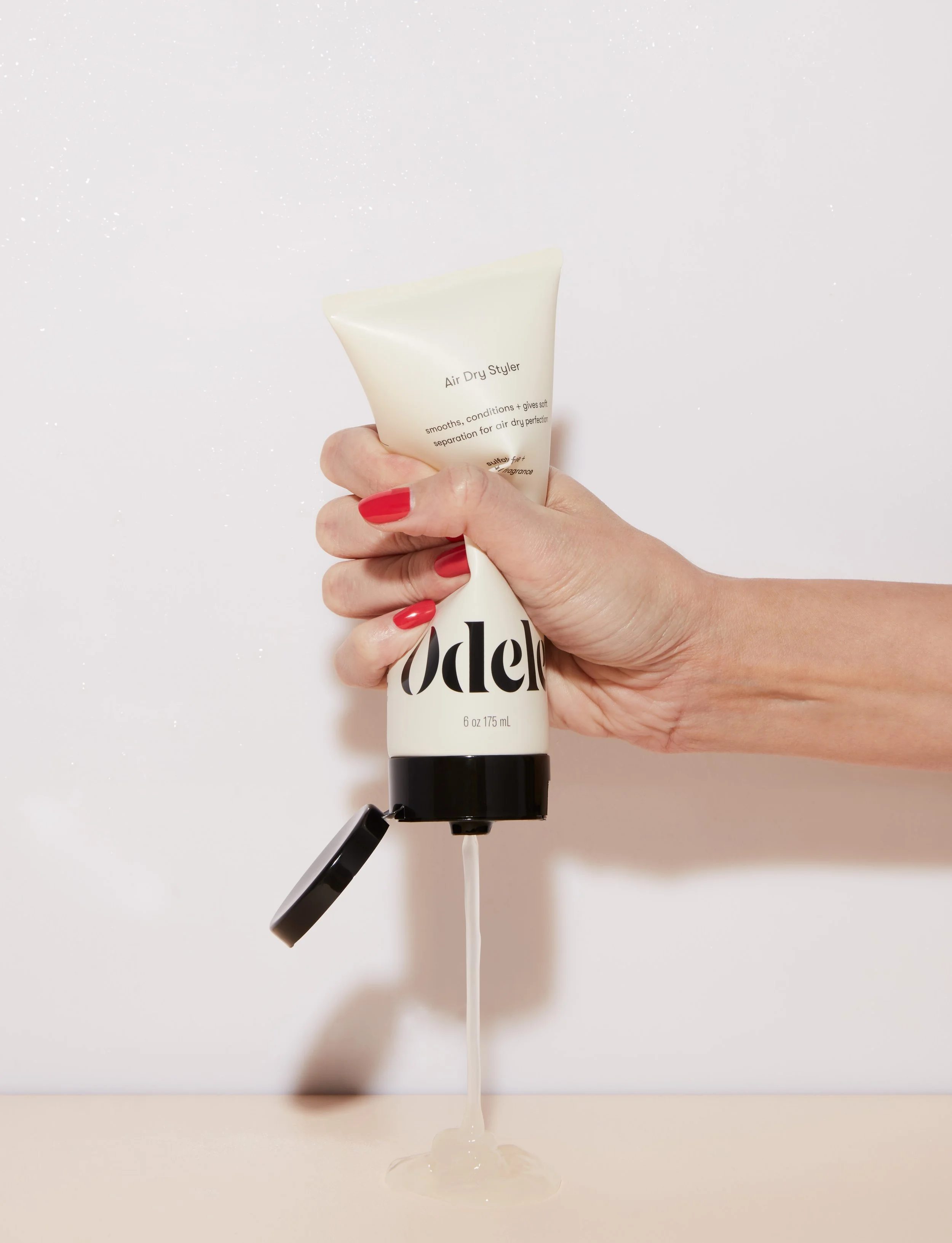 Hand squeezing Odele haircare product featured in a beauty brand digital marketing campaign
