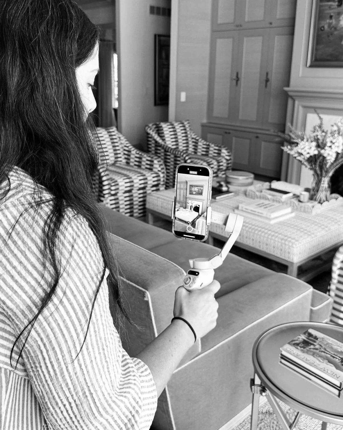 Content creator filming a social media video with a phone gimbal in a styled living room for digital marketing