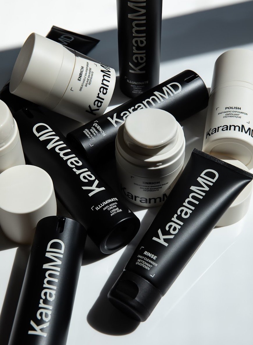 Collection of KaramMD skincare products including tubes, jars, and bottles in black and white packaging arranged on a white surface.