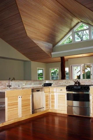 Kitchen with wooden cabinets, granite countertops, stainless steel dishwasher, oven, and a wooden ceiling with large windows.