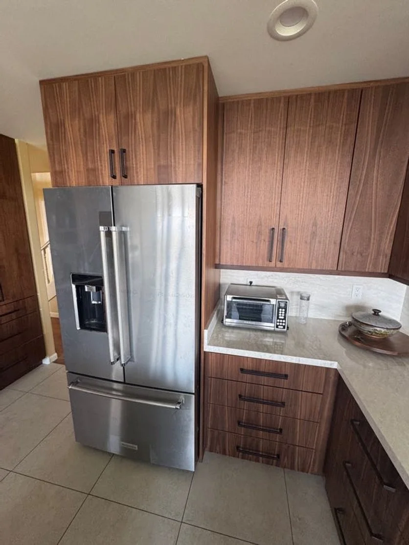 Kitchen with wood cabinets, stainless steel refrigerator, microwave, and countertop with ceramics.