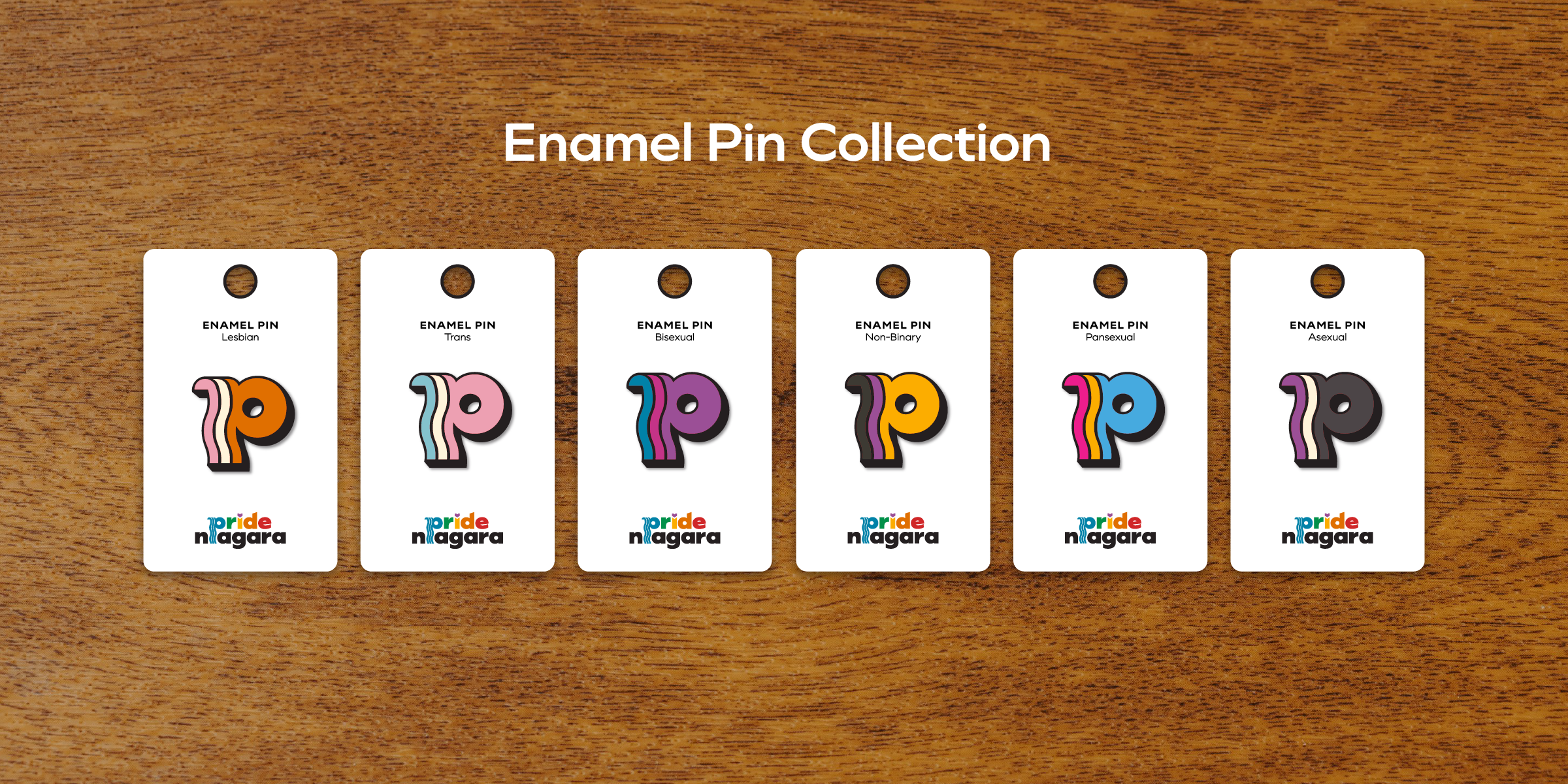 Six enamel pins representing Lesbian, Trans, Bisexual, Non-Binary, Pansexual, and Asexual identities, designed by Steph Parker Designs