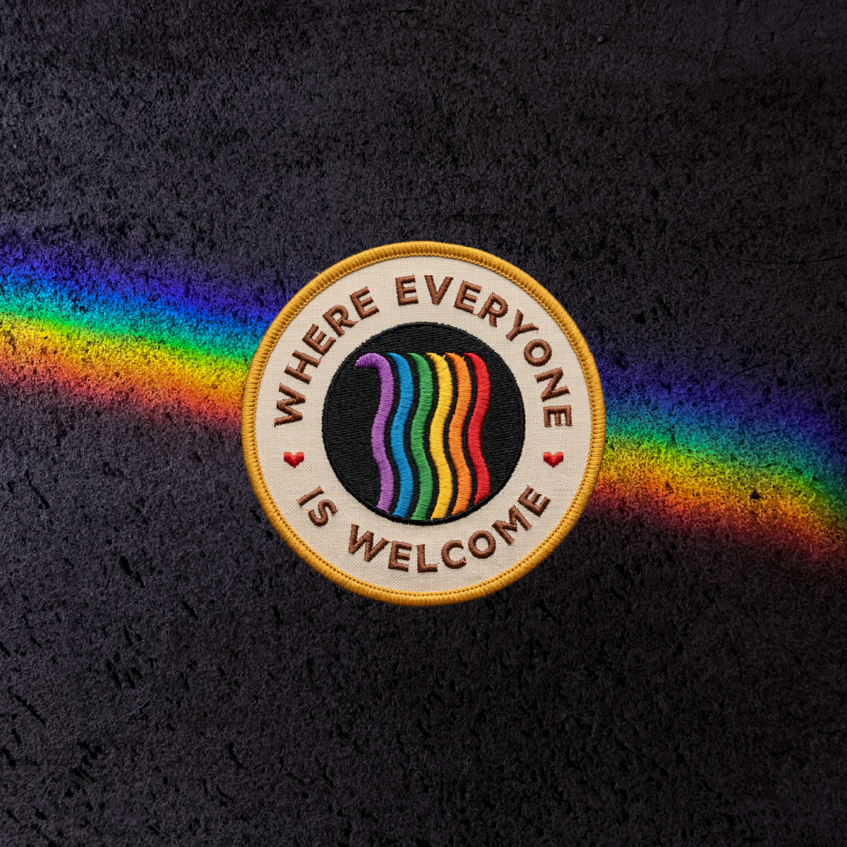 A circular patch design that says "Where everyone is welcome" and has a rainbow waterfall in the middle. Concept designed by Steph Parker Designs