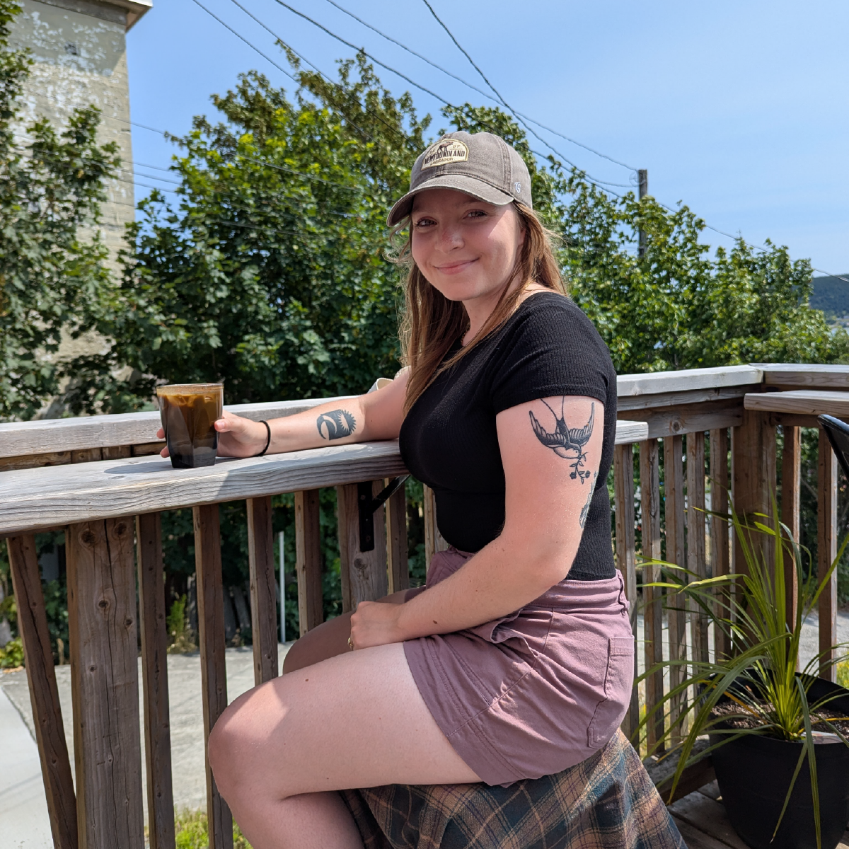 Brand Designer Steph Parker sitting on a chair outside at a local cafe's wooden patio.