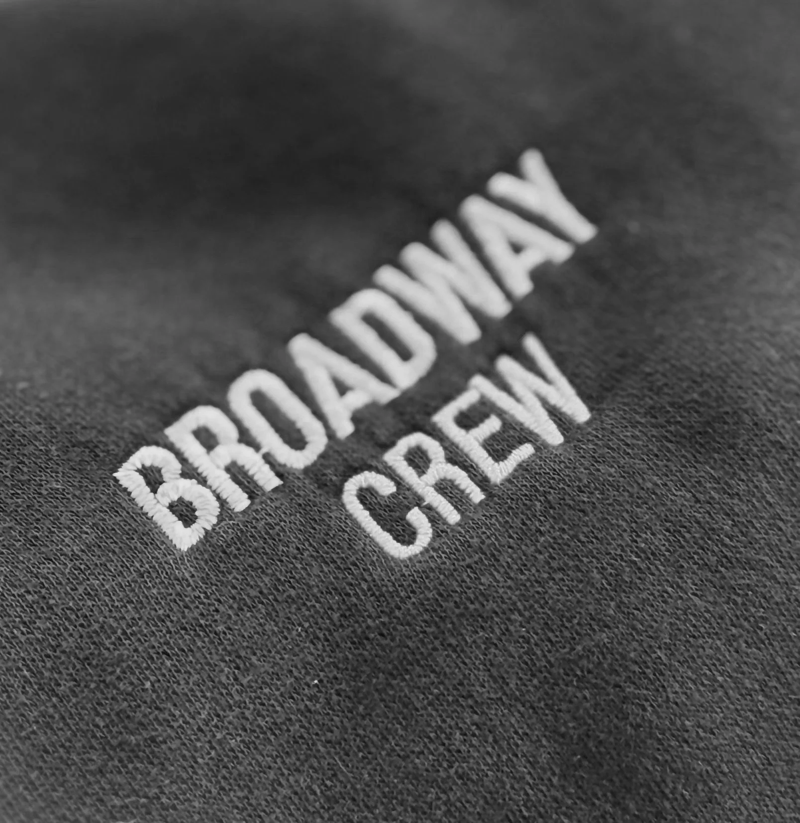 Close-up of embroidered text 'BROADDAY CREAT' on black fabric.