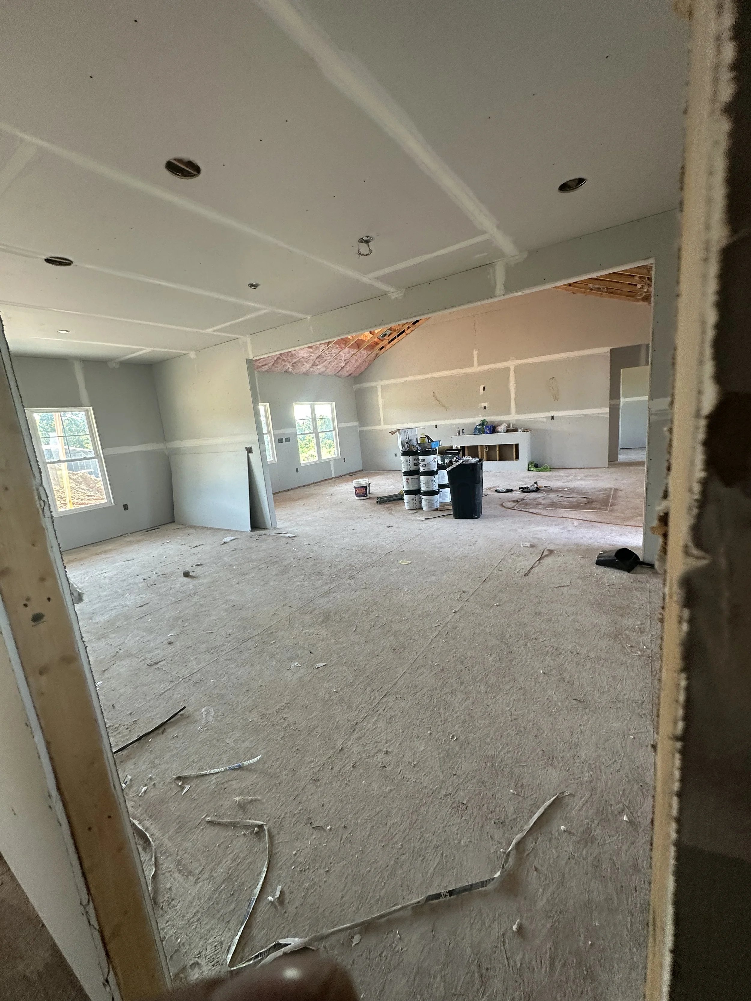 Room under construction with drywall, windows, and construction materials.