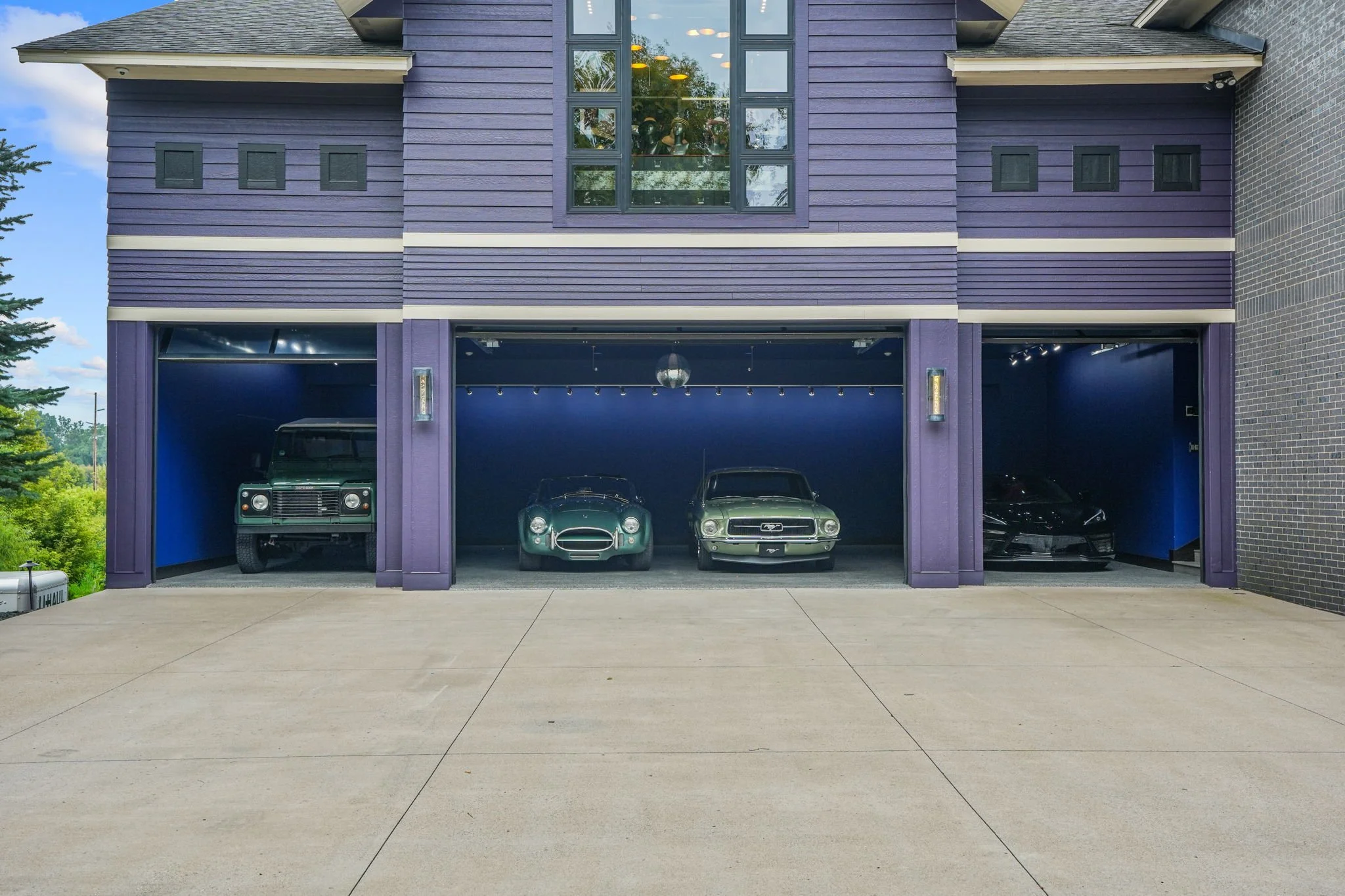 Three cars stored in a modern garage with purple siding and blue interior walls.