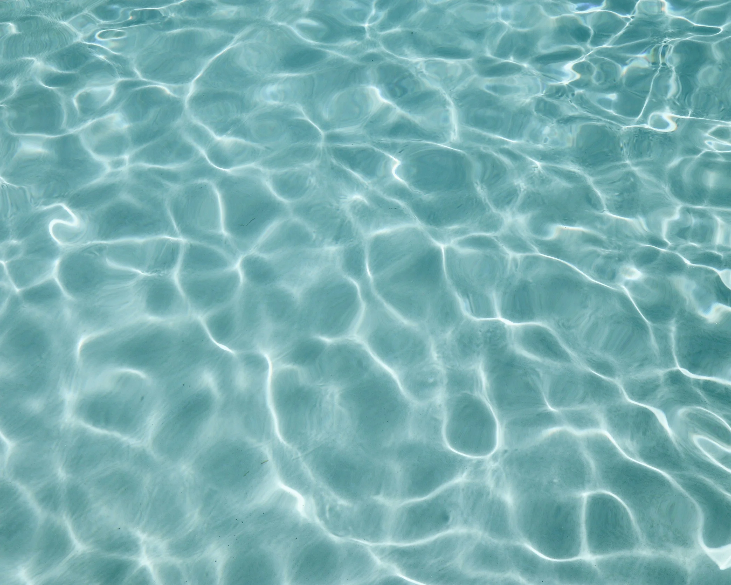 Clear blue water with sunlight reflecting on the surface.