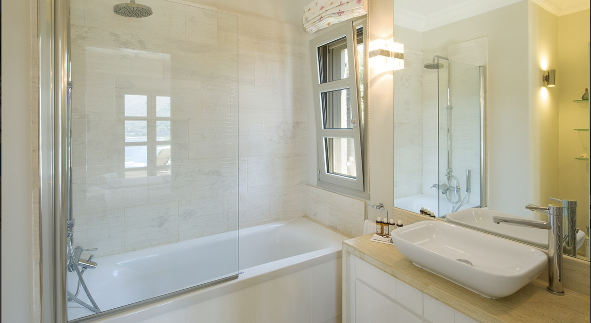 Modern bathroom with bathtub, window, and vessel sink with a mirror.