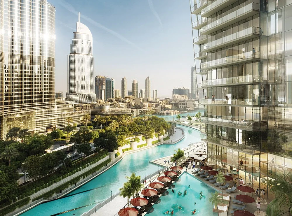 Cityscape view with tall skyscrapers, a river or canal, and a modern hotel or residential building with a pool and outdoor seating area.