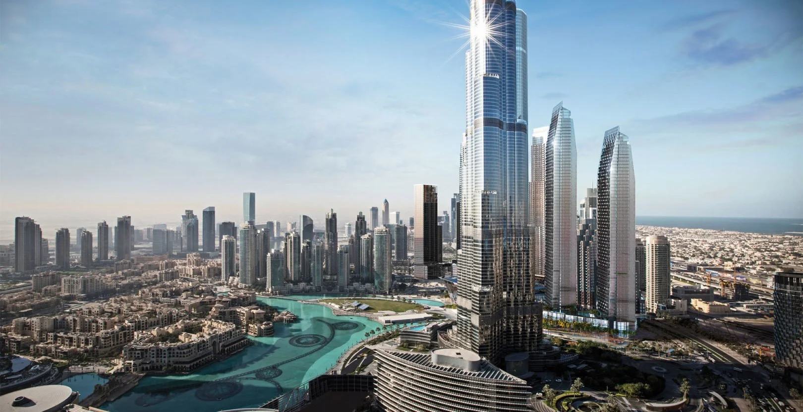 Aerial view of Downtown Dubai, featuring the Burj Khalifa and surrounding skyscrapers with a man-made lake and urban landscaping in foreground, under a partly cloudy sky.