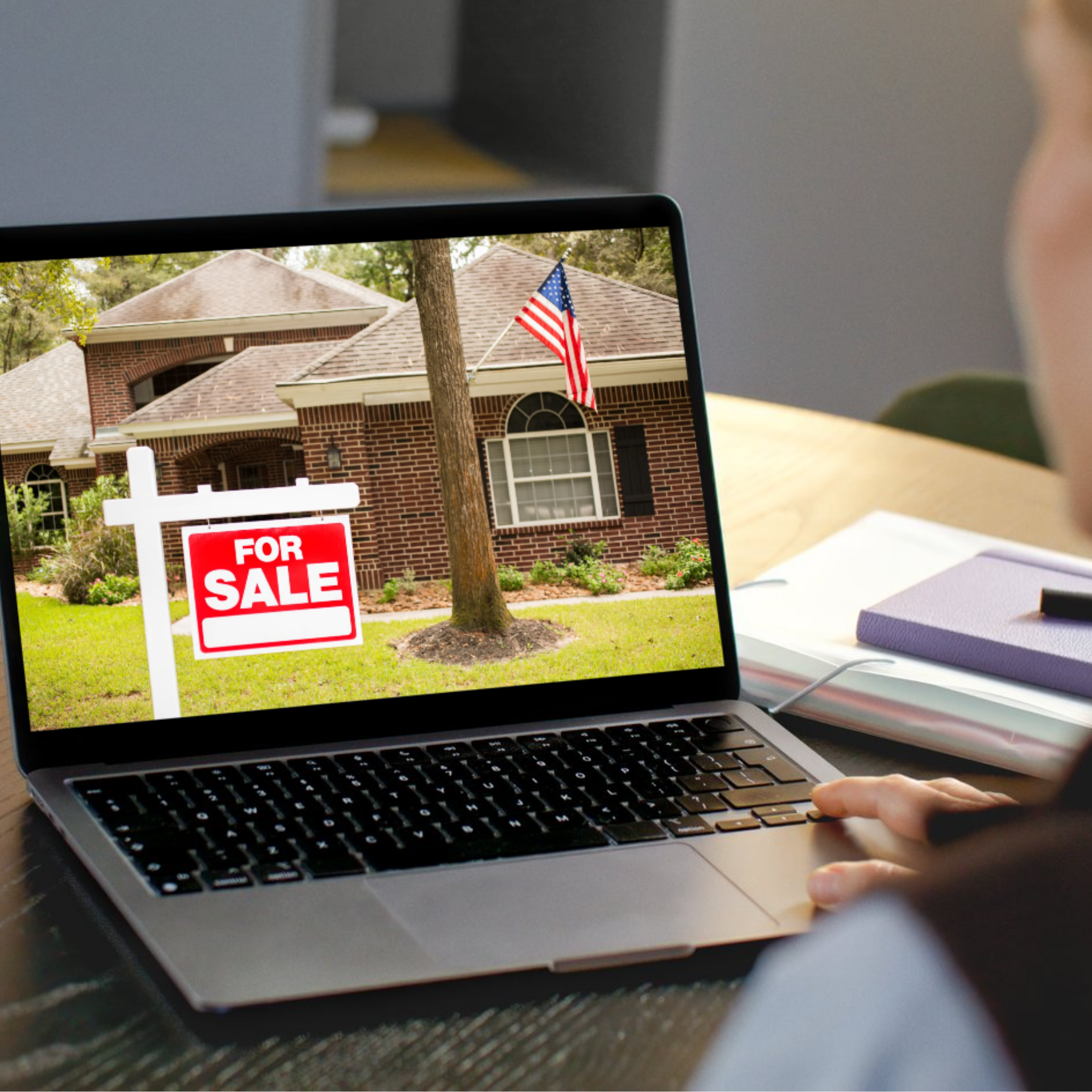Laptop displaying a House with a 'For Sale' sign on the lawn and an American flag in the background.