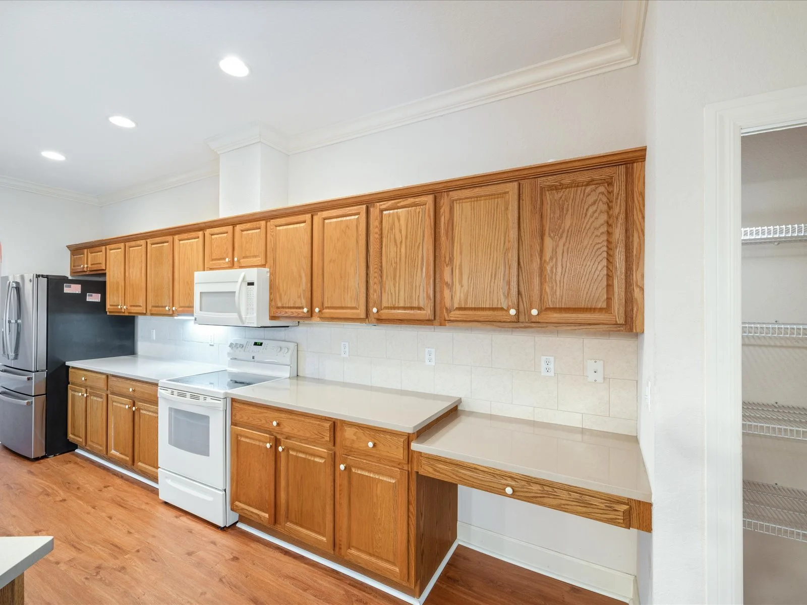 Before the Flip: kitchen with original wooden cabinets, white appliances including a stove and microwave, and a pantry with wire shelving, showing the existing layout prior to Flip Design strategy and staging.