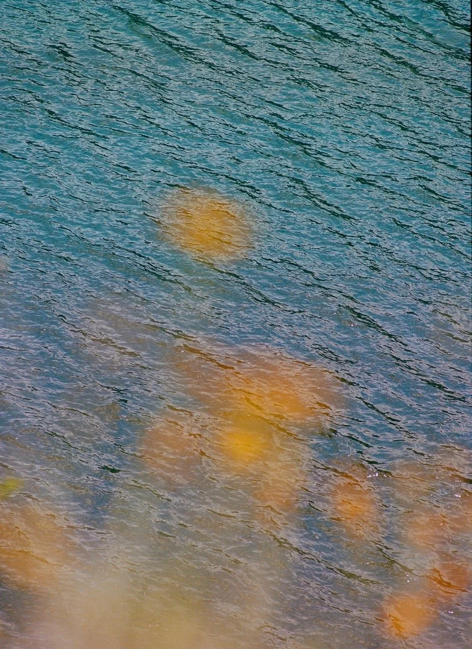 Blurred view of colored balls behind a glass surface with water ripples.