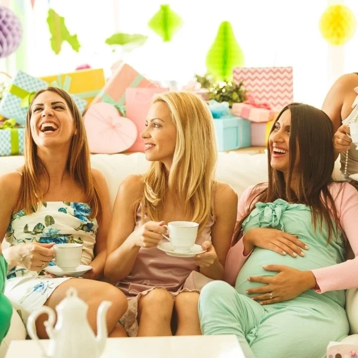 Expectant mother and friends enjoying coffee together at baby shower celebration.