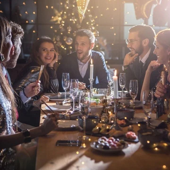 Friends gathered around festive dinner table, laughing and talking together.