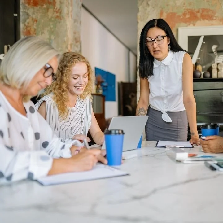 Team members working together at table with takeaway coffee cups during meeting.