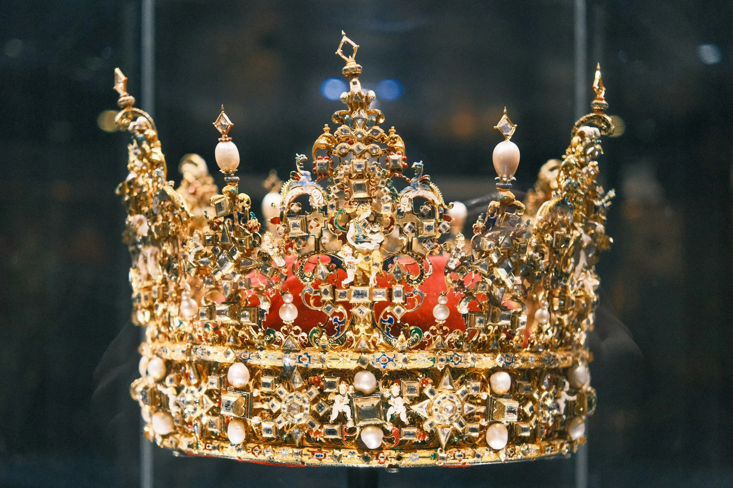 A regal crown with intricate gold metalwork, adorned with various sized pearls and sparkling gemstones