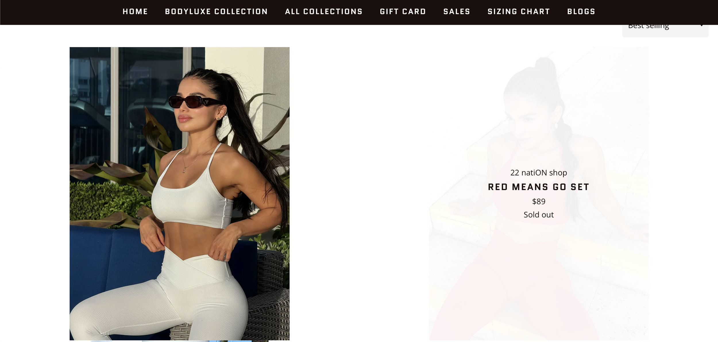 A woman with long dark hair wearing large sunglasses, a white crop top, and matching high-waisted leggings seated outdoors near a building with large windows and plants, during daytime.