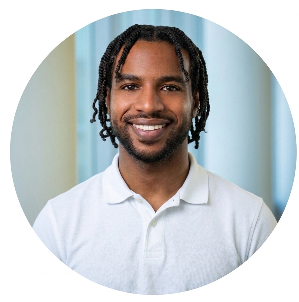 Close-up portrait of a smiling young man with dreadlocks, wearing a dark jacket over a green shirt.