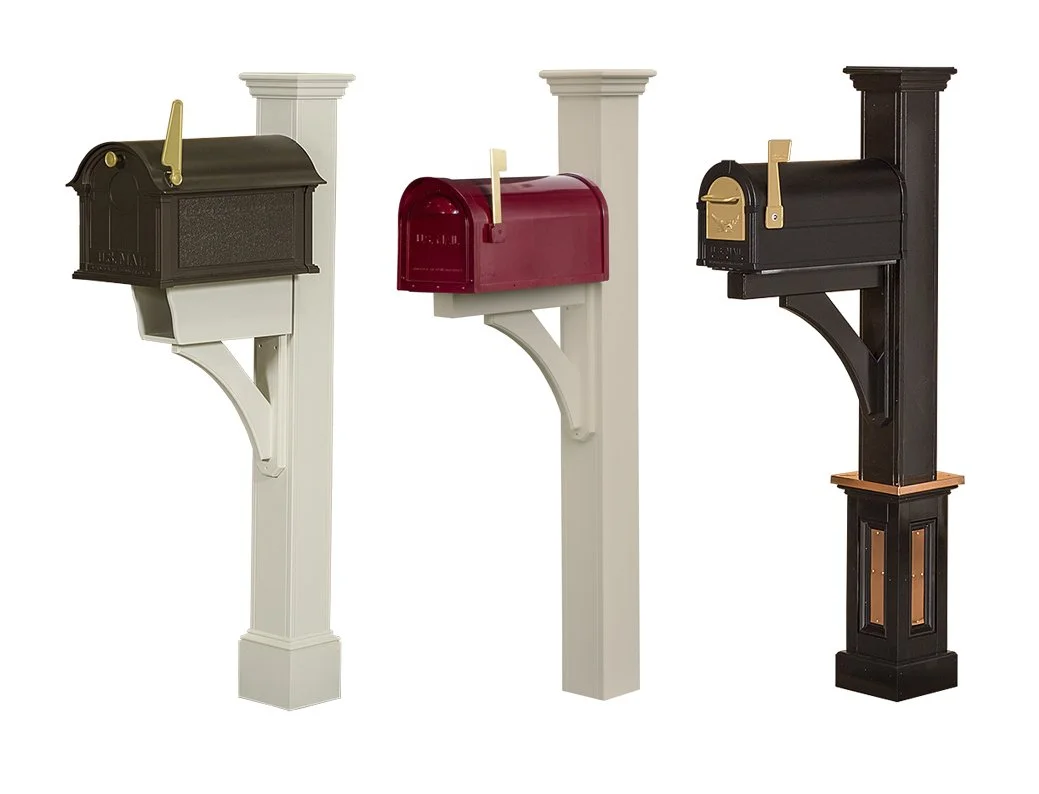 Three decorative postal mailboxes in different colors and styles mounted on white and black posts.