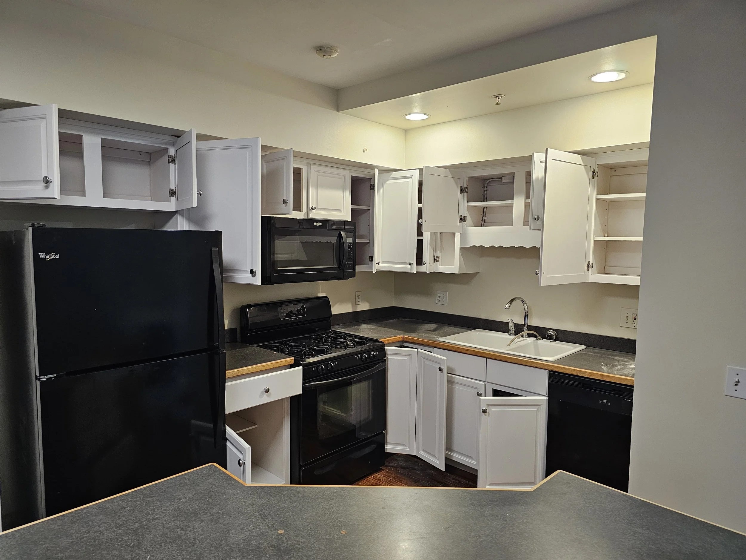 White cabinets with black appliances really modernize and offer a contrast. Cabinet refinishing.
