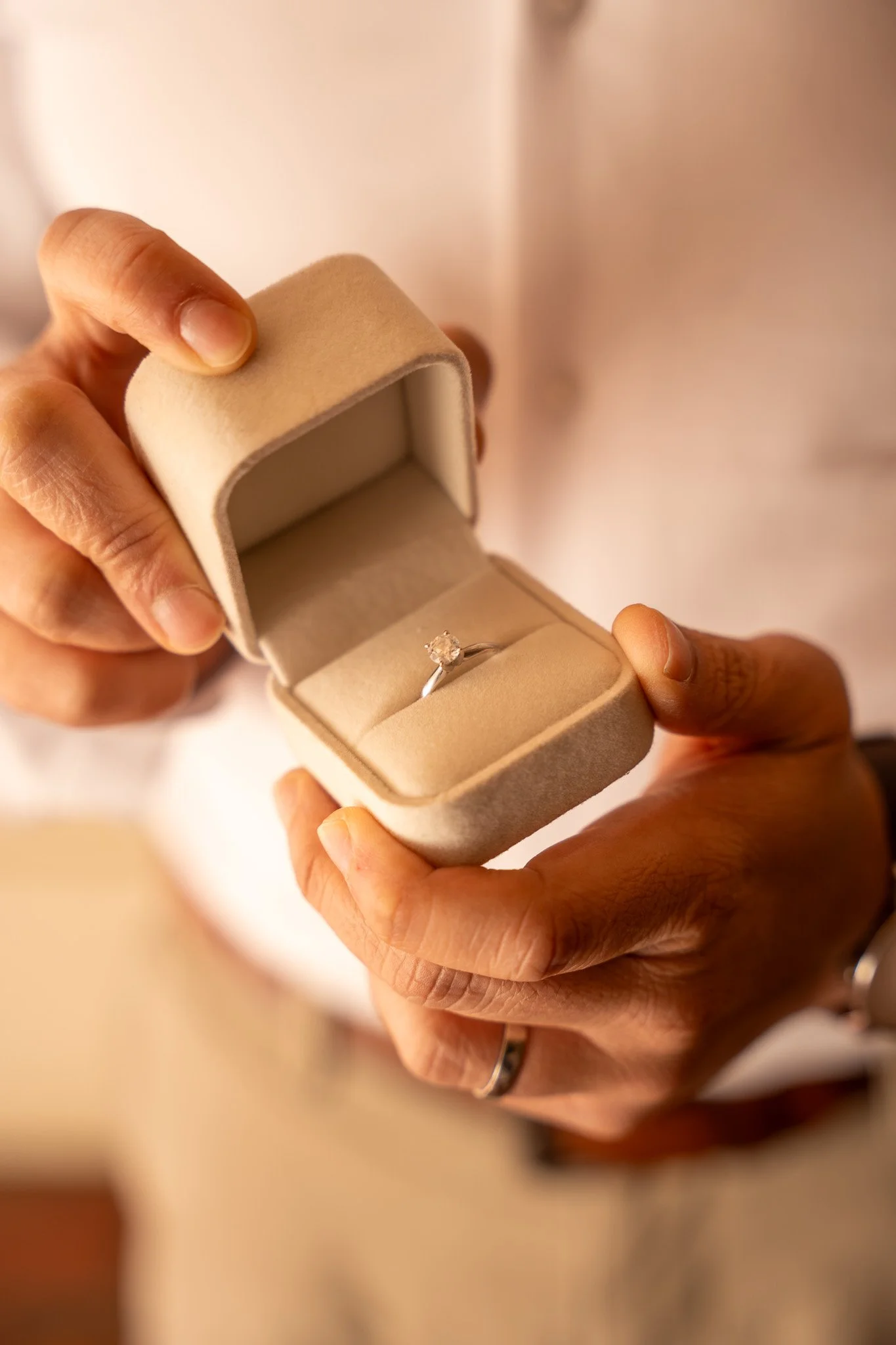 A person holding an open jewelry box with a ring inside.