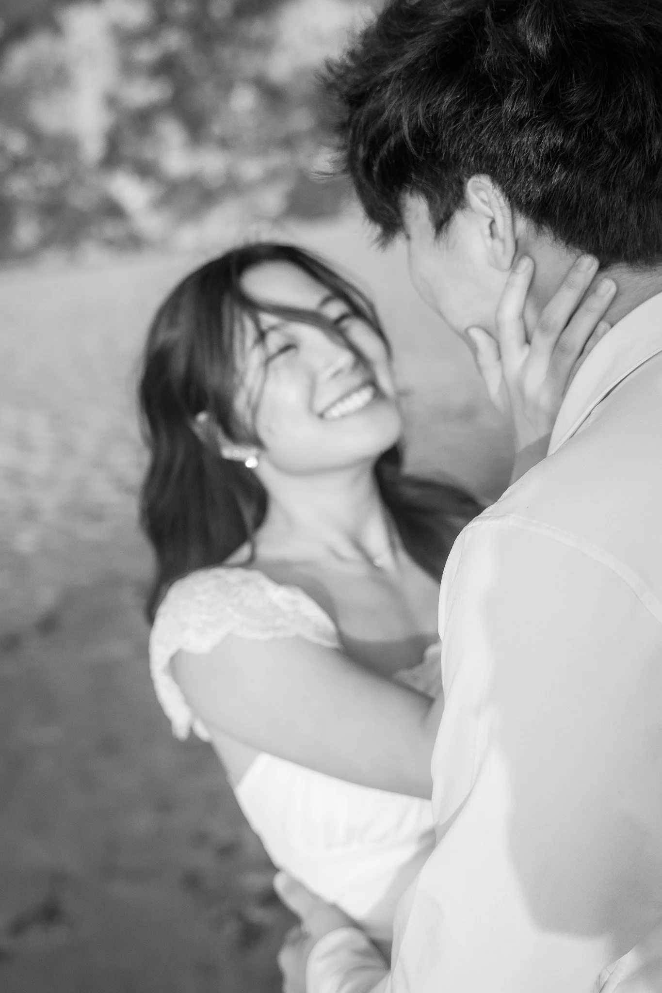 A man holding a woman's face tenderly, both smiling with closed eyes, in a romantic moment.