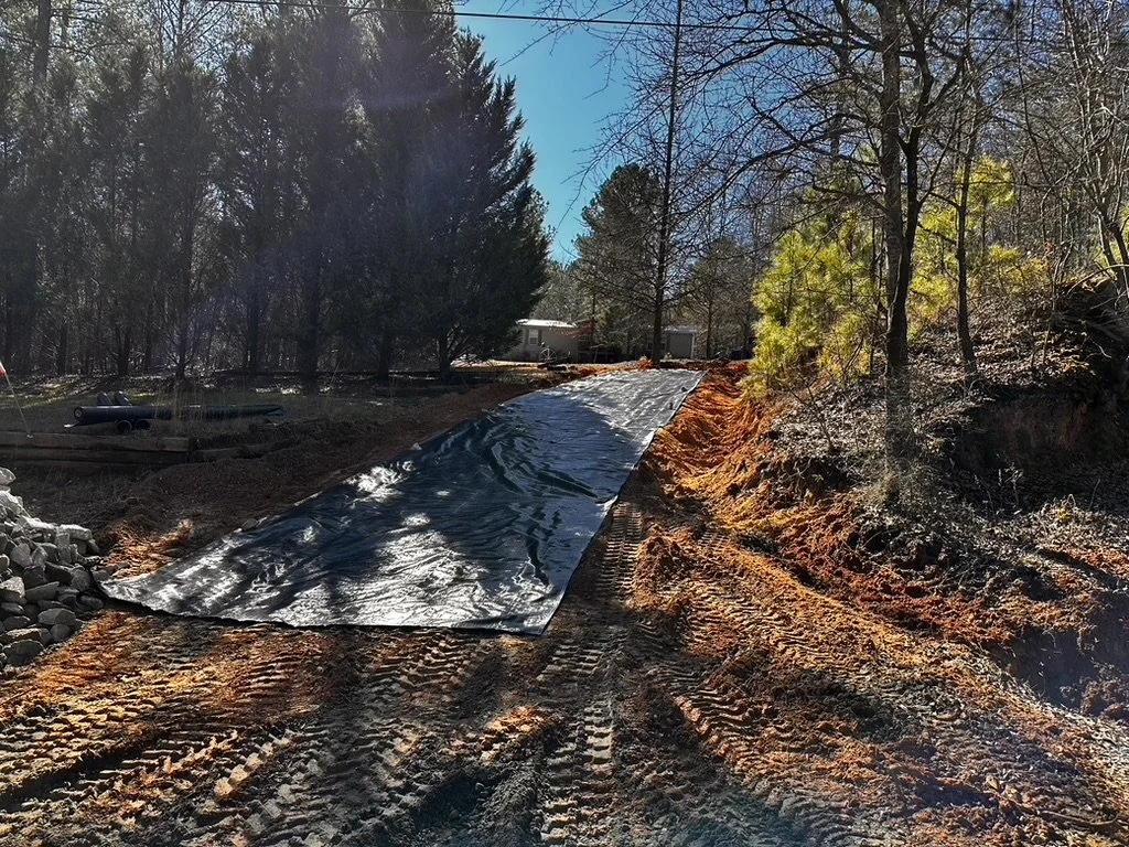 Geotextile fabric installed beneath the driveway area for soil stabilization and erosion prevention, part of ASG Dirtworx site preparation.