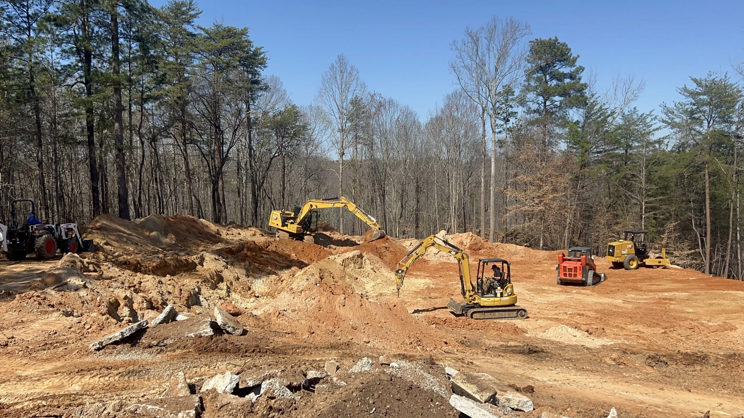 Excavators, dozers, and compactors are operating in coordination during a major earthmoving and grading phase by ASG Dirtworx.