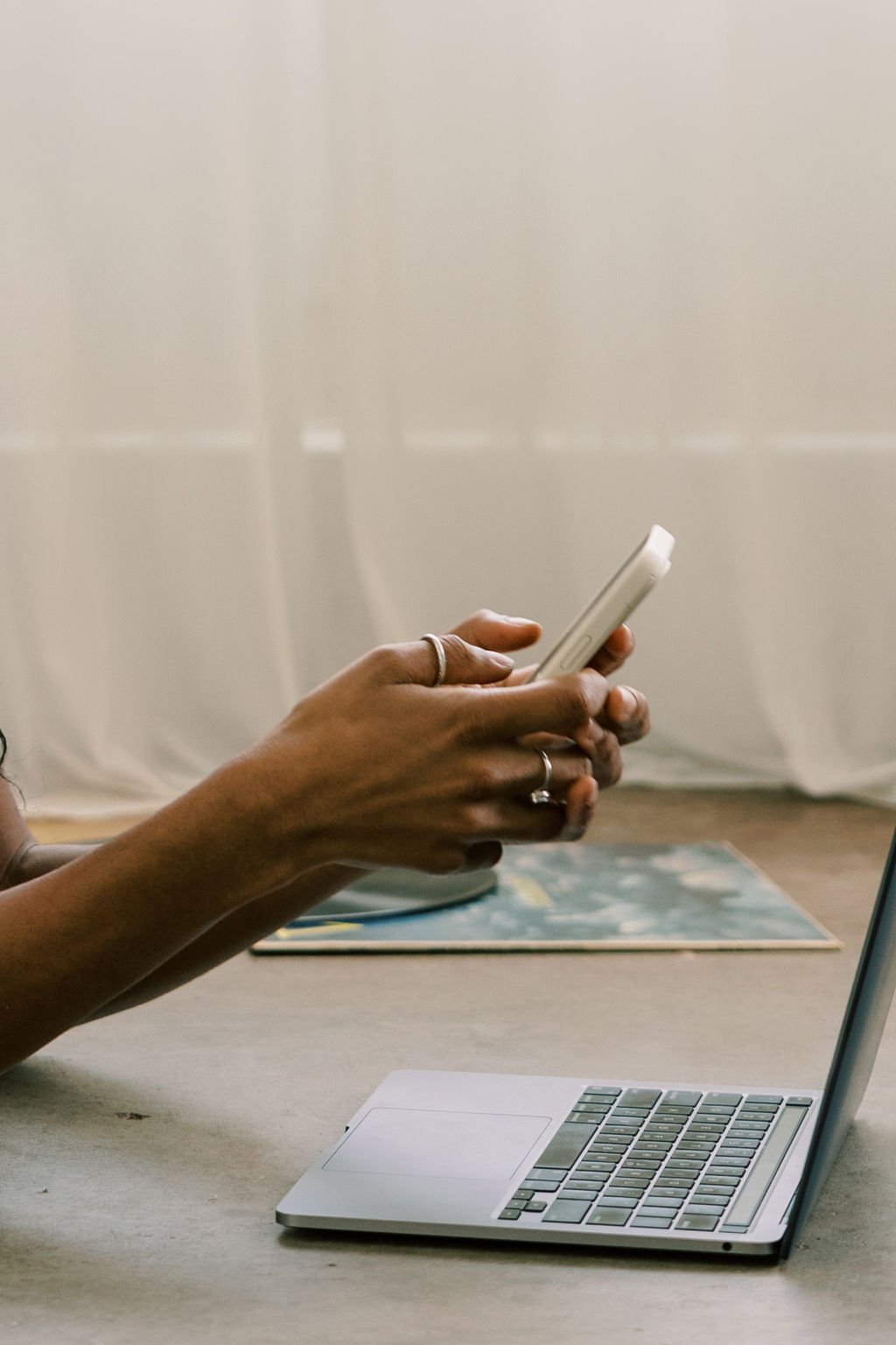 Une personne utilisant un téléphone portable, avec un ordinateur portable ouvert sur une surface plane.
