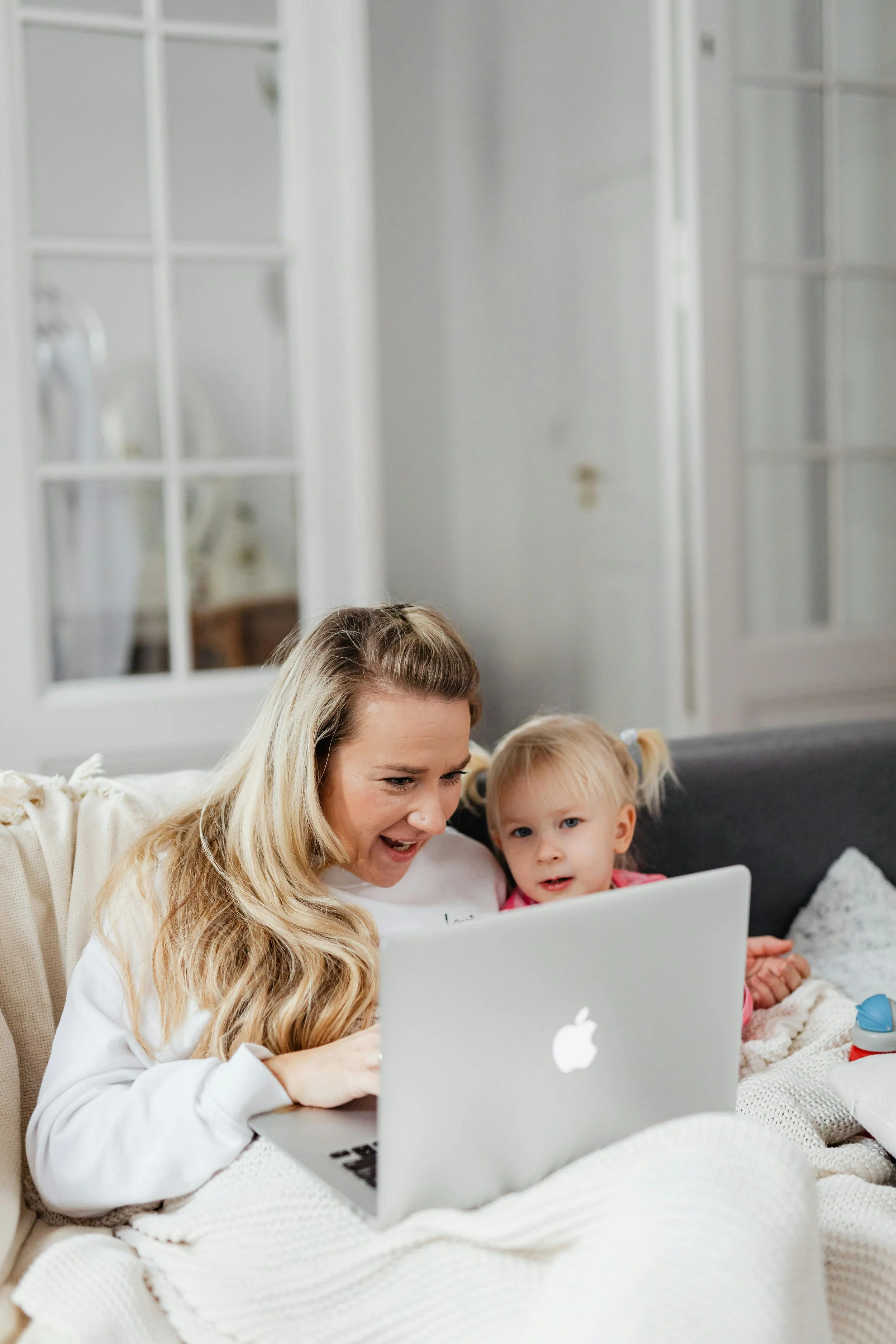 Une femme et une petite fille regardent un ordinateur portable dans un salon confortable.