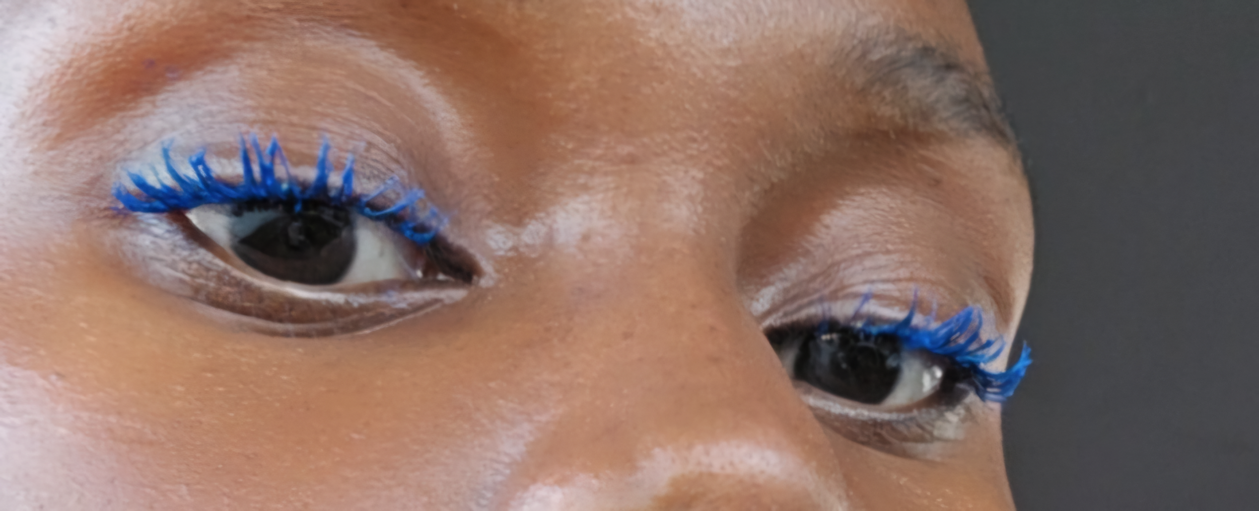 Hilary Biaku | Black Female Model, Creative Strategist, Content Creator, Public Speaker, and Life Coach — Close-up of a person's eyes with bright blue eyelashes.