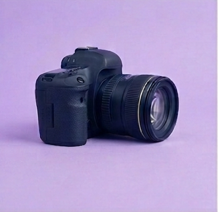 A digital camera with a large lens on a purple surface with a purple background.