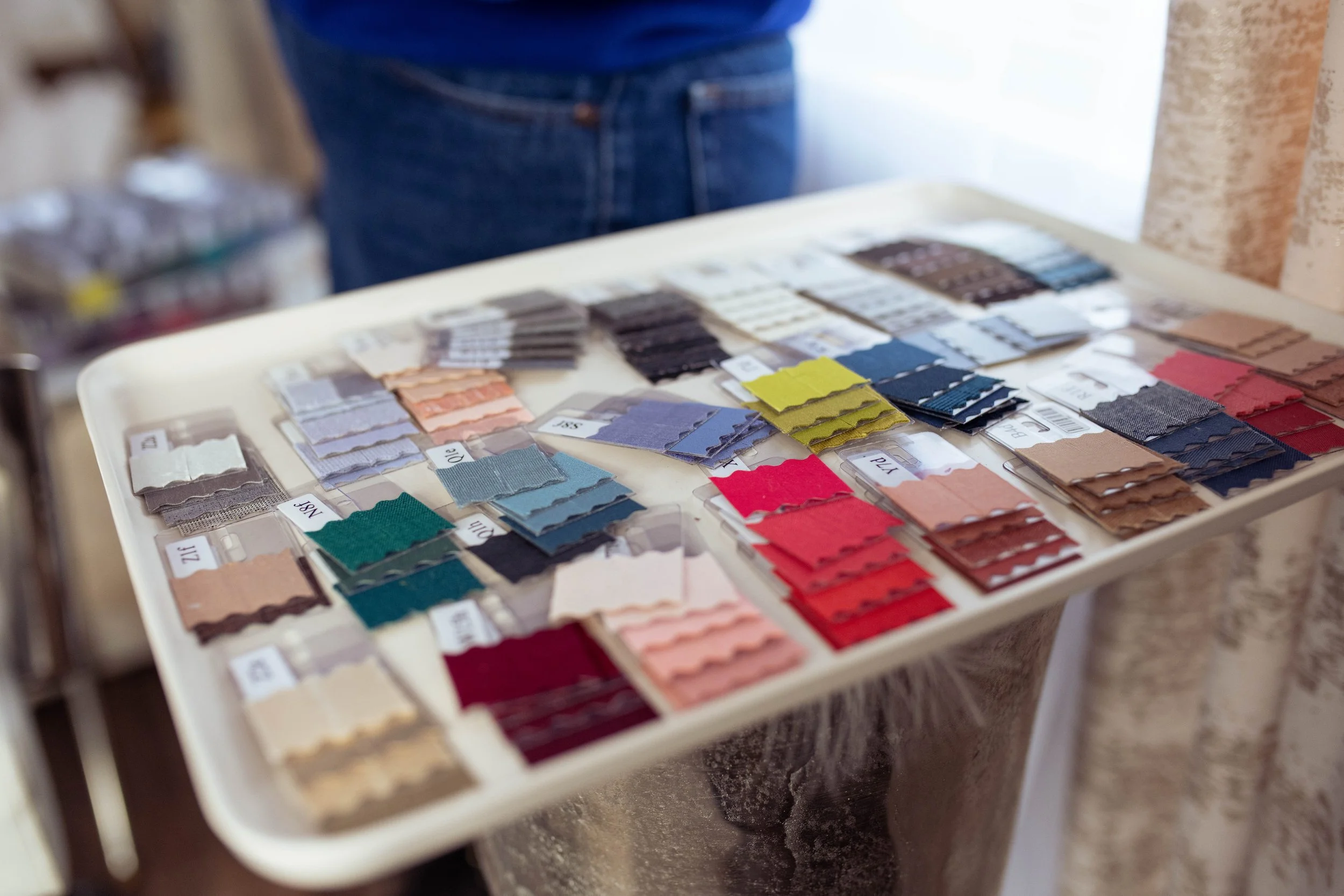 Display of fabric swatches used for color analysis in various colors on a table with a person standing behind.