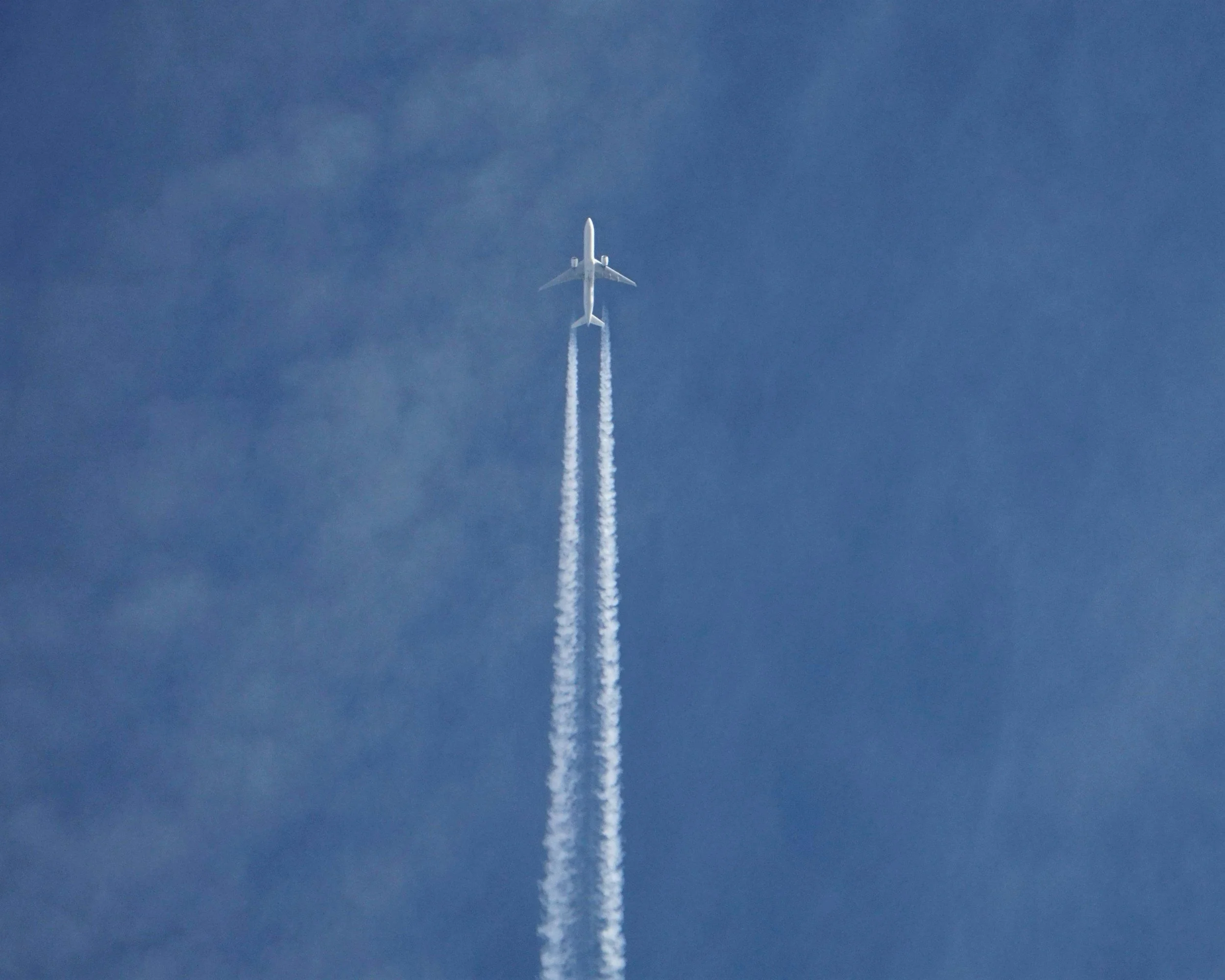 An airplane flying high in the sky, leaving white contrails behind.