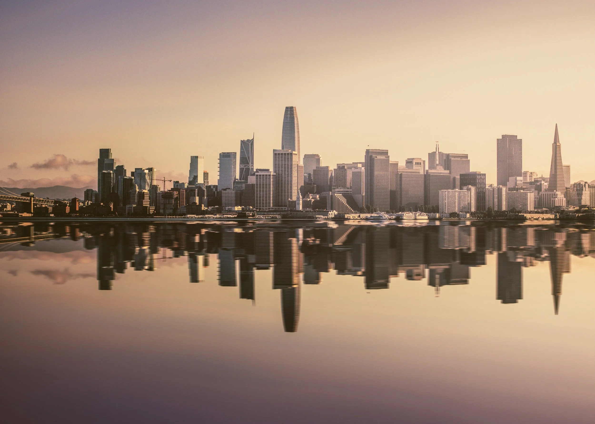 San Francisco skyline at sunset reflected in the water.